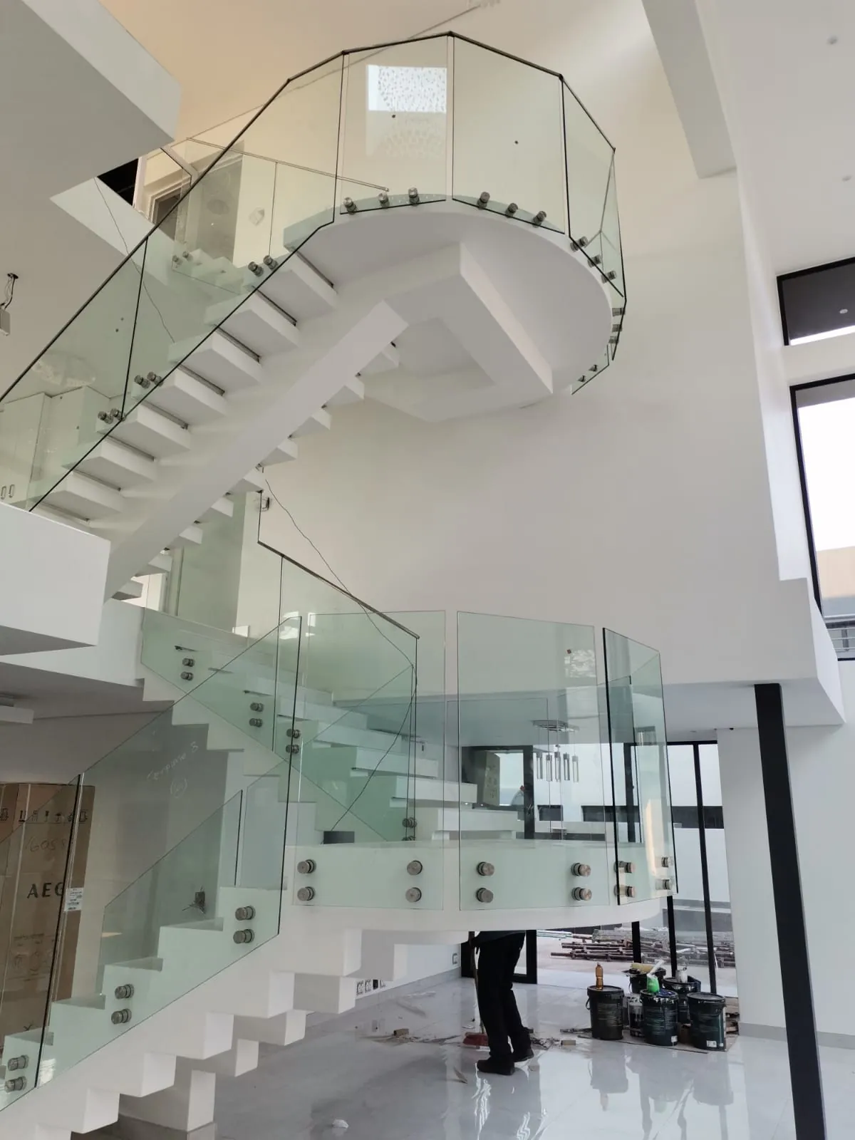 Frameless glass staircase balustrade with stainless steel fixings in a double-volume entrance