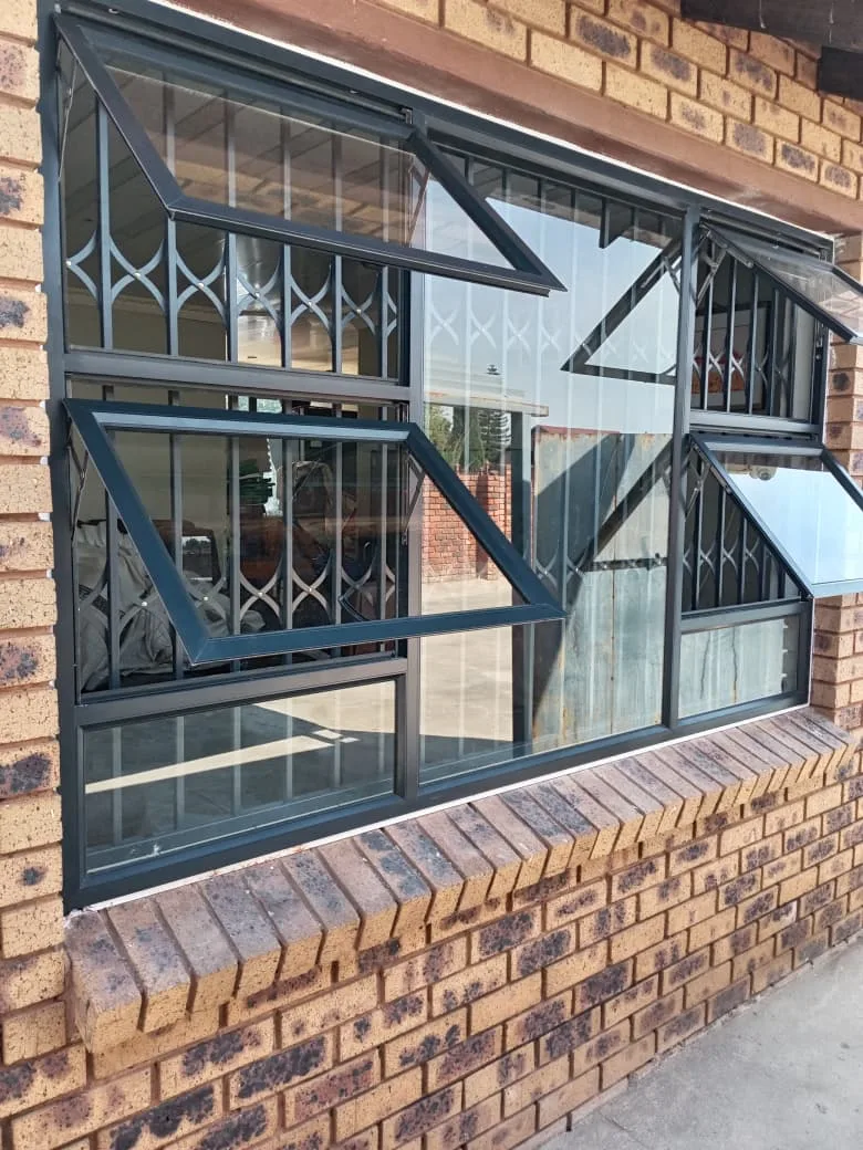 Charcoal aluminium windows with retractable burglar proofing fitted behind the glass on a face-brick home
