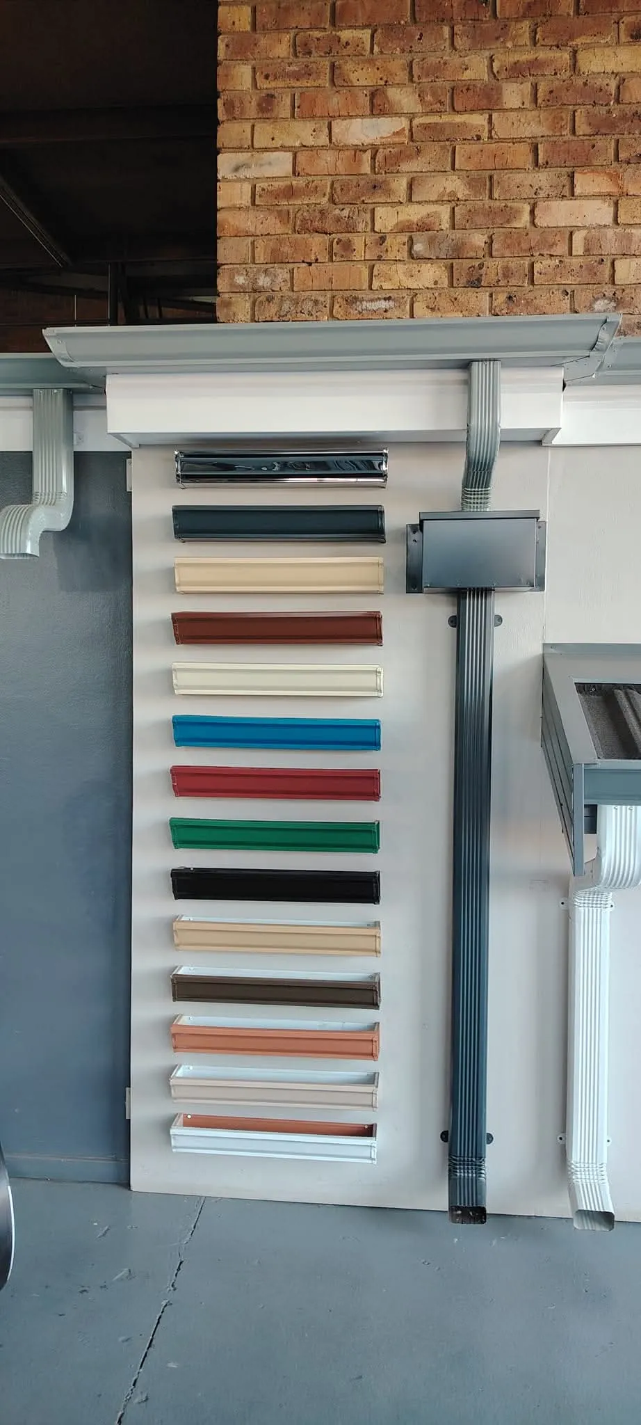 Display board of colour-coated steel gutter samples with a matching downpipe