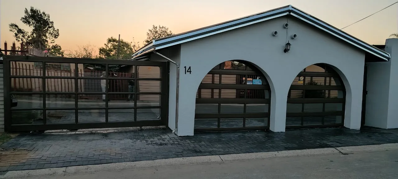 Two arched aluminium and glass garage doors with a matching aluminium sliding gate