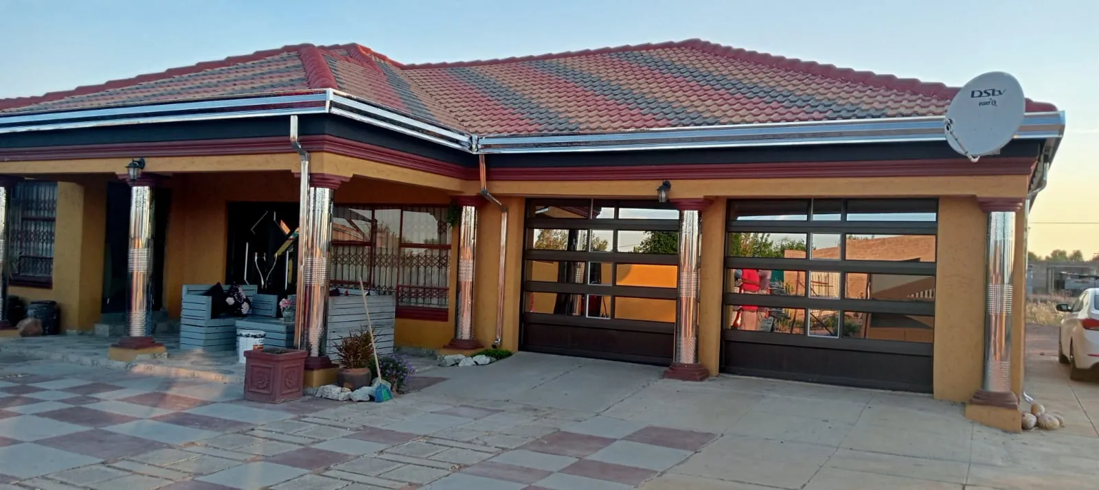 Home with stainless steel fascia boards and downpipes, galvanised gutters, stainless steel pillar coverings and two single aluminium garage doors