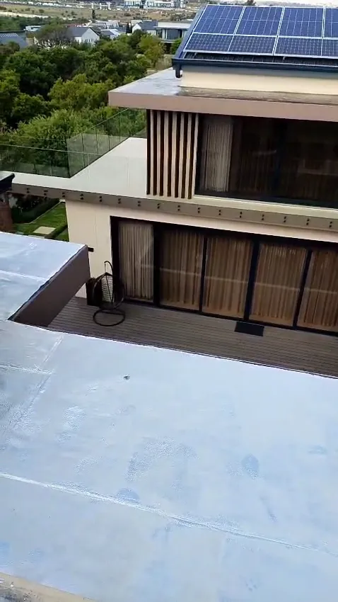 Flat concrete roof finished with torch-on waterproofing, beside a double-storey home